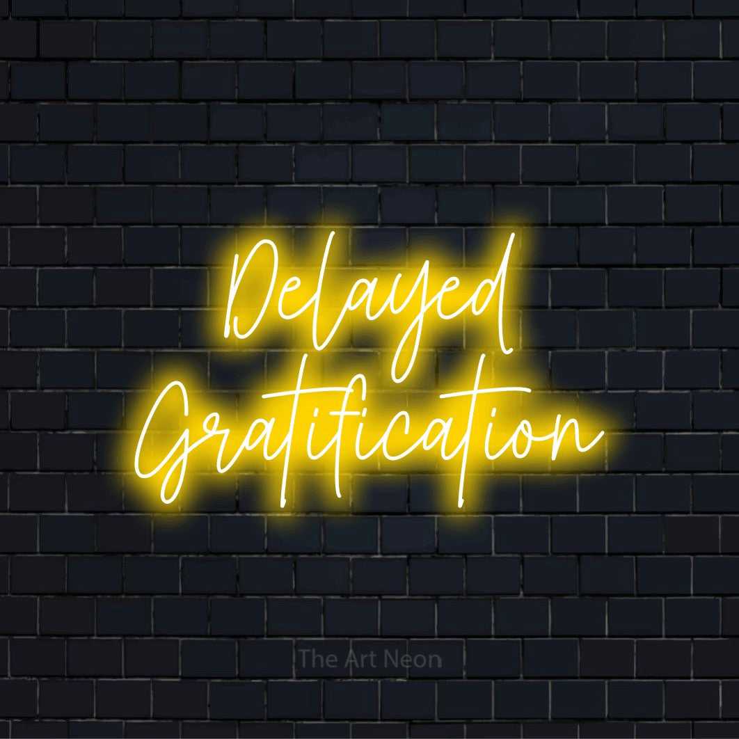 "Delayed Gratification" text design with neon effect on a black brick wall