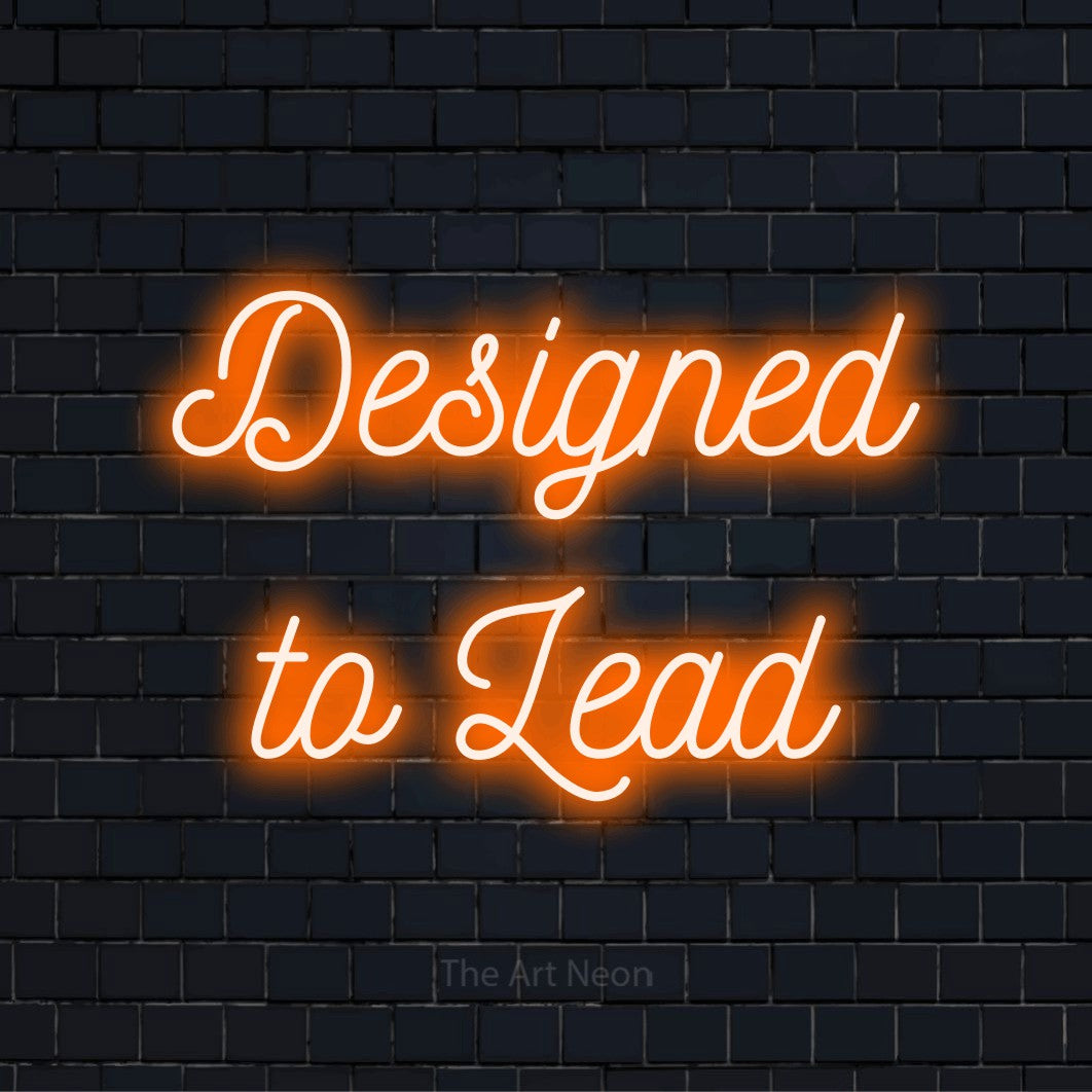 "Designed To Lead" script-style LED neon sign on a black brick wall