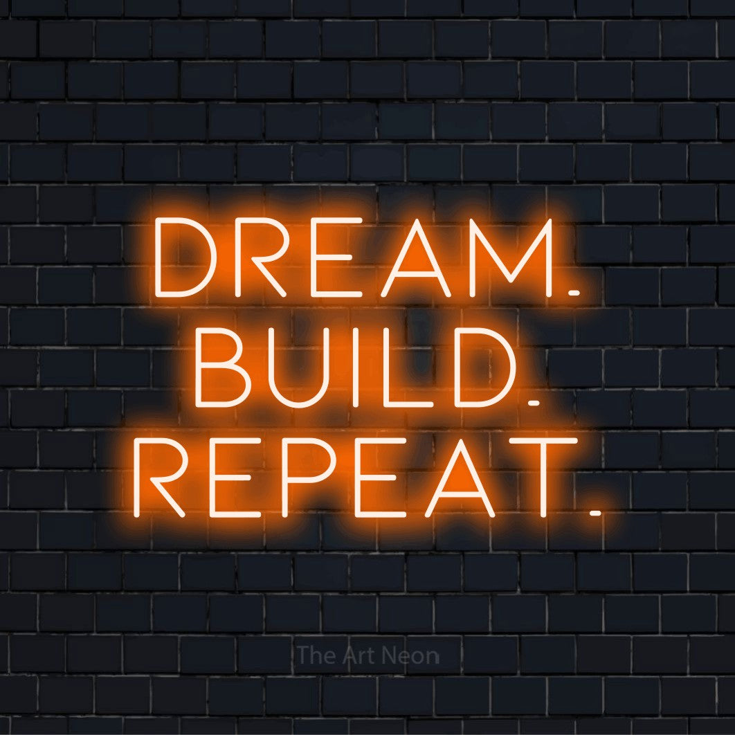 "Dream. Build. Repeat." glowing LED neon sign on a black brick wall