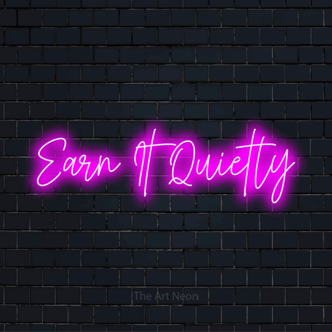 "Earn It Quietly" script-style LED neon sign on a black brick wall