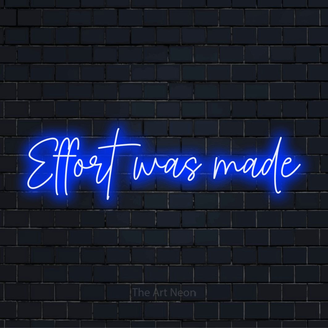 "Effort Was Made" script-style LED neon sign on a black brick wall