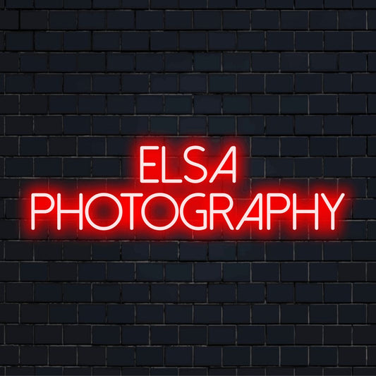 Elsa Photography Custom Name Neon Sign, glowing neon text on dark brick background