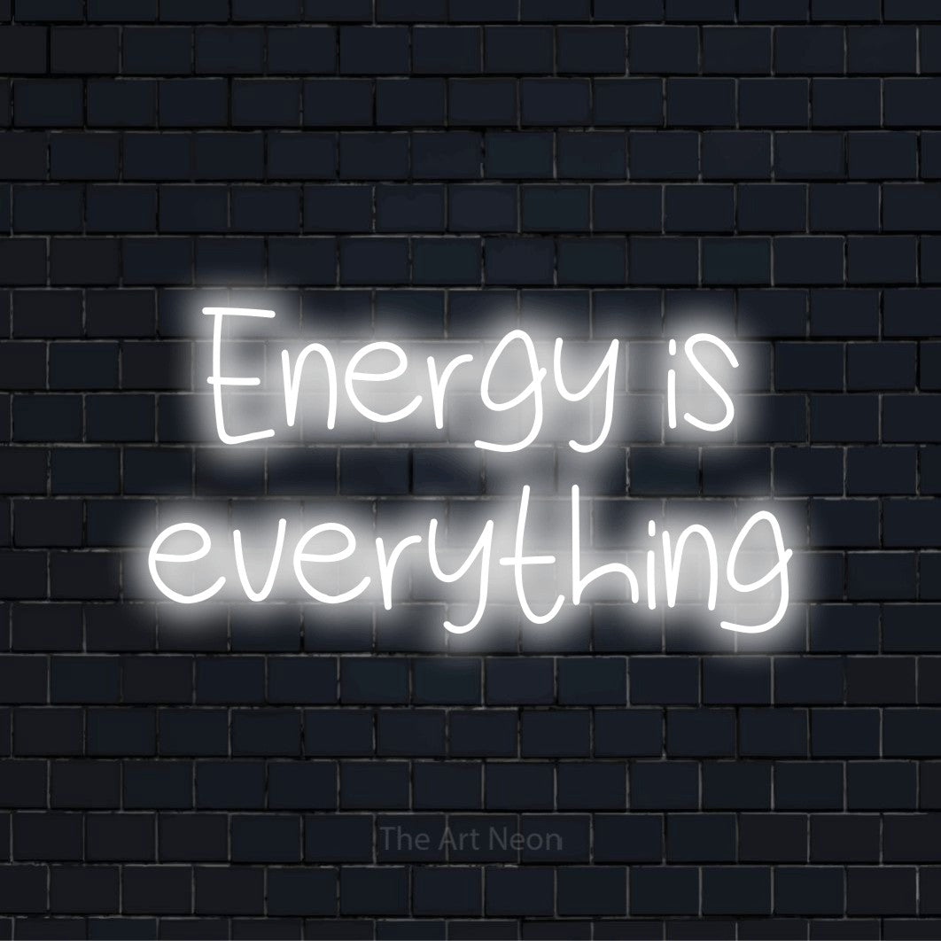 "Energy Is Everything" script-style LED neon sign on a black brick wall