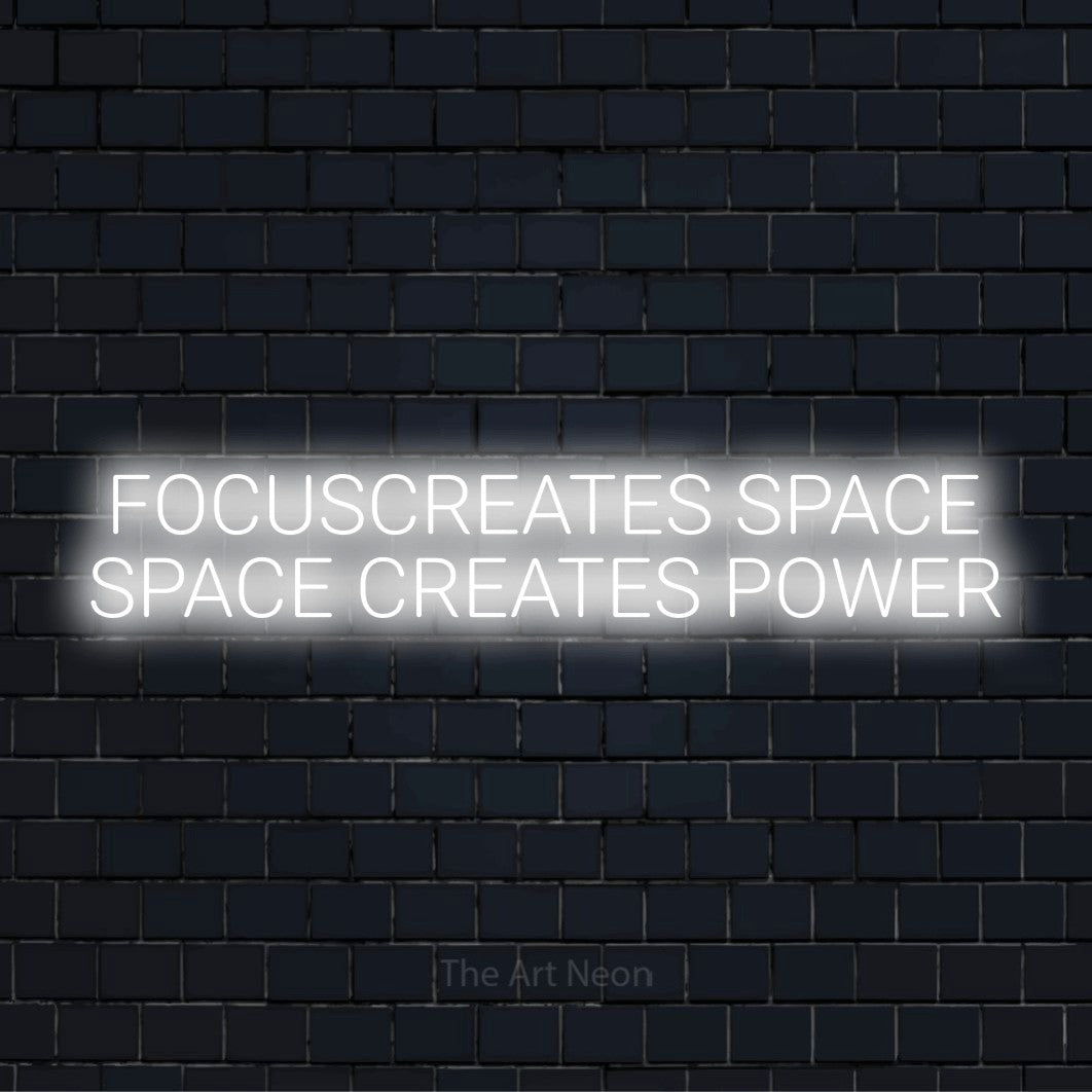 "Focus Creates Space Space Creates Power" neon text design on a black brick wall