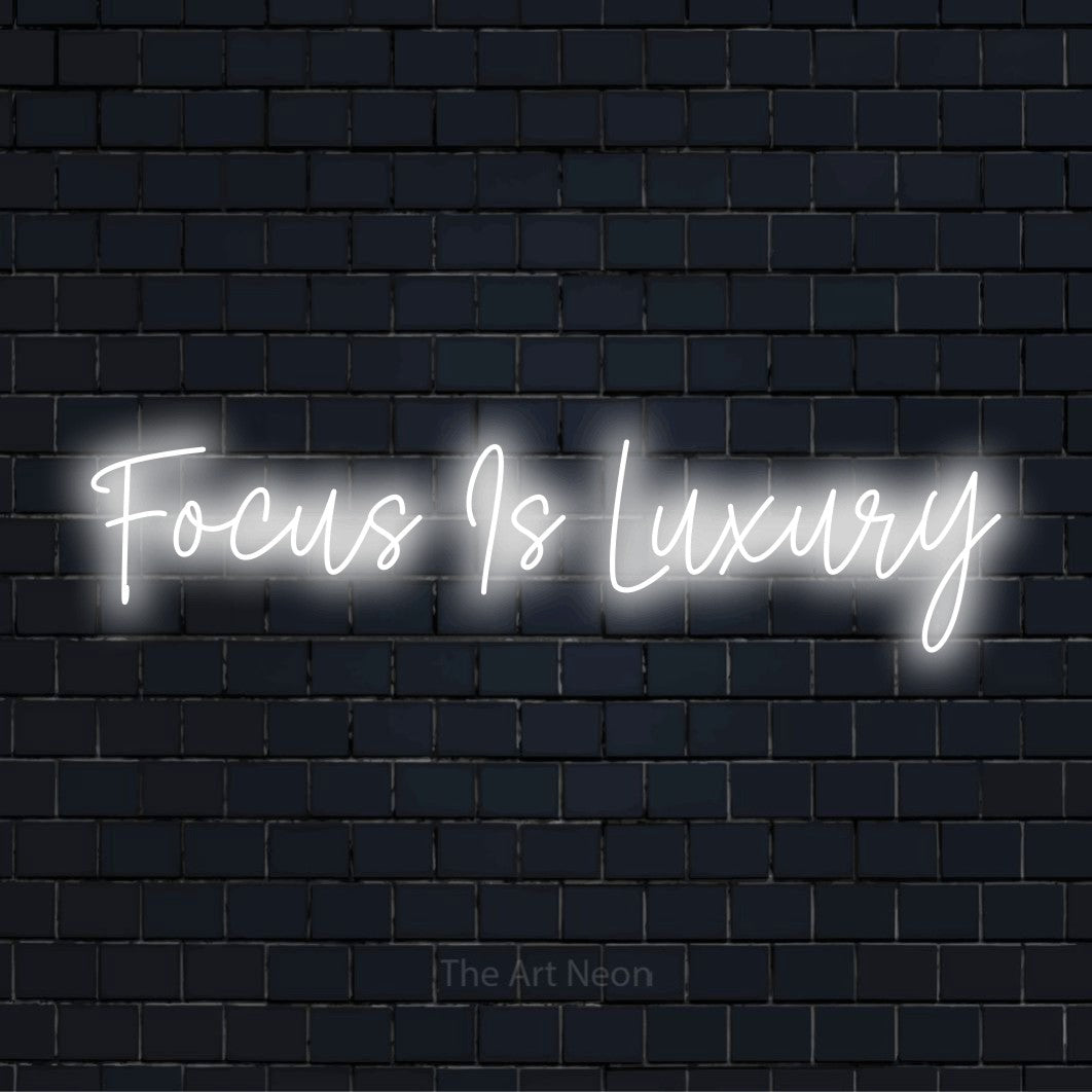 "Focus Is Luxury" LED neon sign on a black brick wall