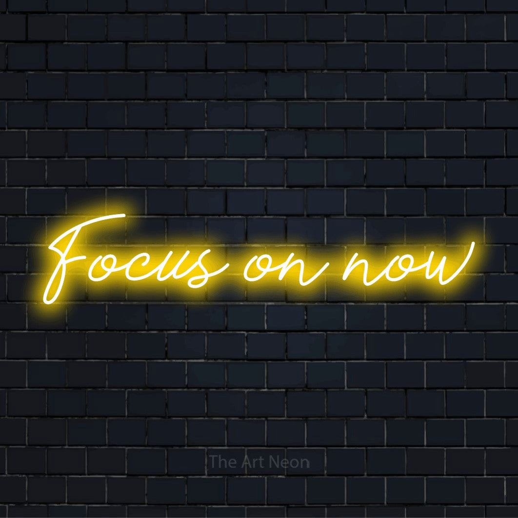 "Focus On Now" neon text design on a black brick wall