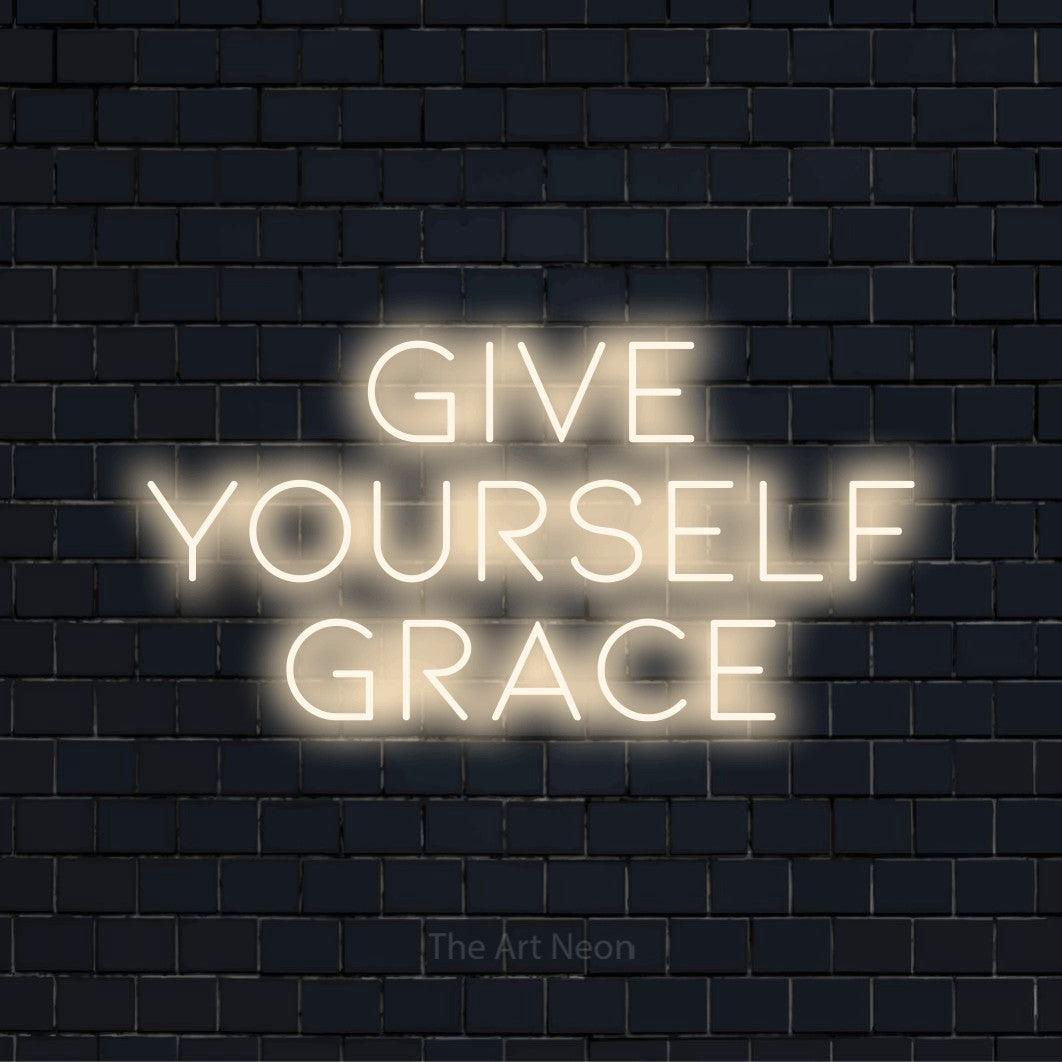 "Give Yourself Grace" LED neon sign on a black brick wall
