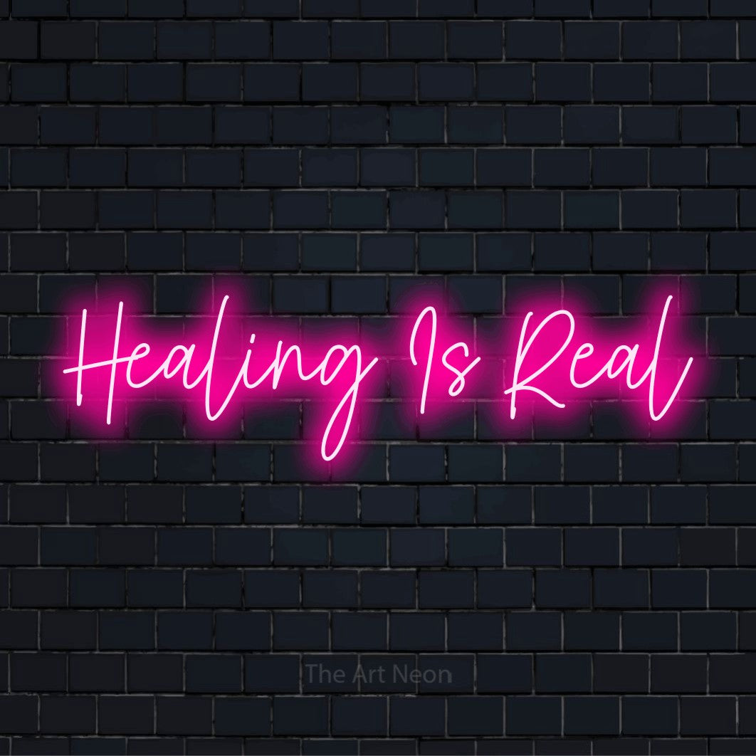 "Healing Is Real" LED neon sign on a black brick wall