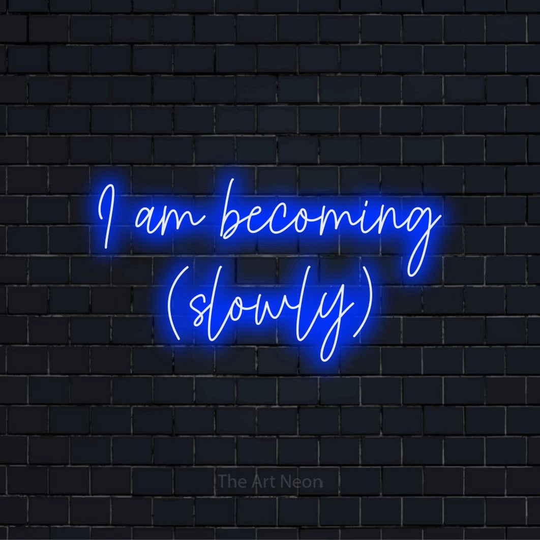 "I Am Becoming (slowly)" LED neon sign on a black brick wall