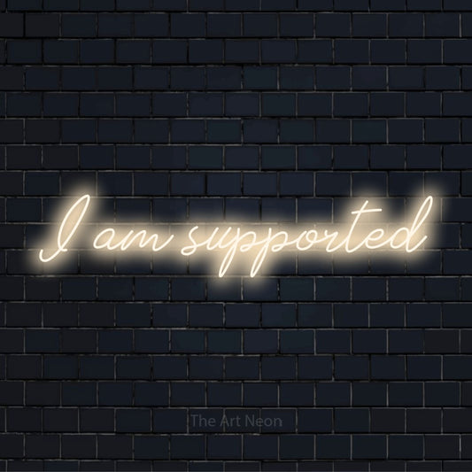 "I Am Supported" neon text design on a black brick wall