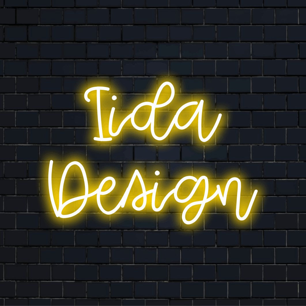 Iida Design Custom Name Neon Sign, glowing wall decor against black brick wall