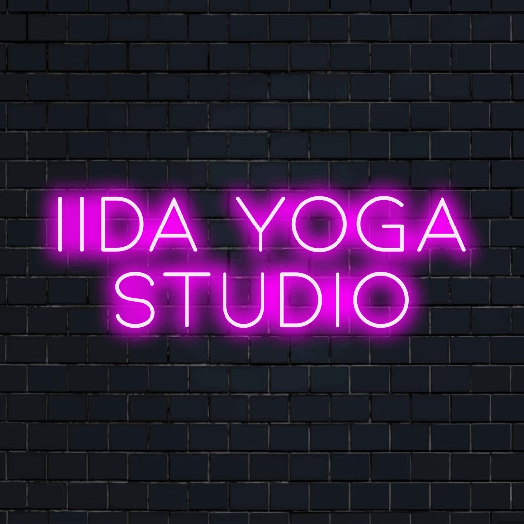Iida Yoga Studio Custom Name Neon Sign, glowing wall decor on dark brick background