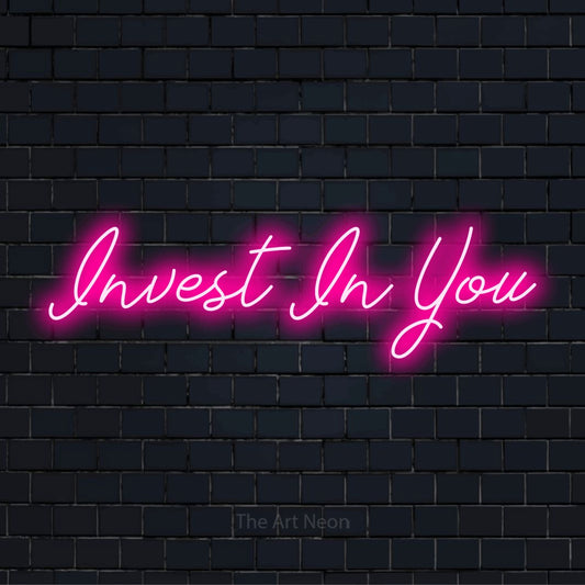 "Invest In You" glowing LED neon sign on a black brick wall