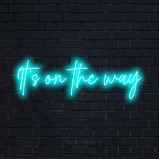 "It’s On The Way" LED neon sign on a black brick wall
