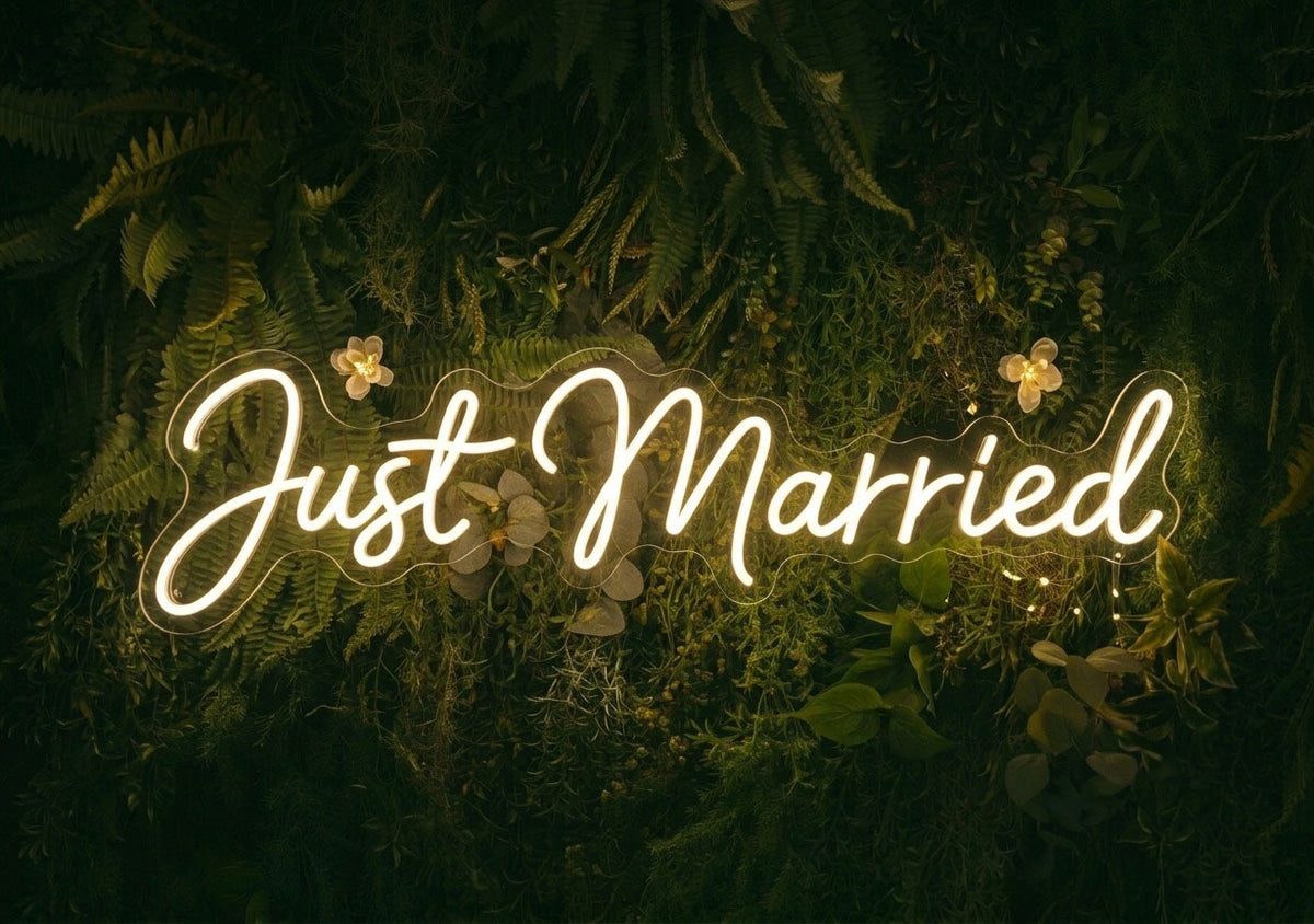 Warm white Just Married LED neon sign displayed on a greenery wall