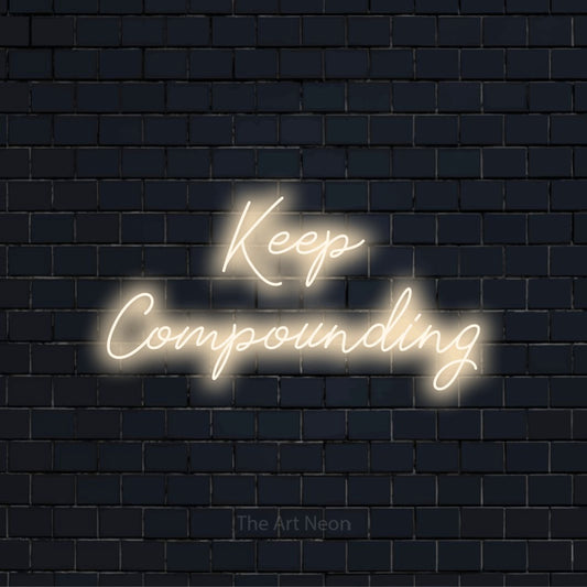 "Keep Compounding" glowing LED neon sign on a black brick wall