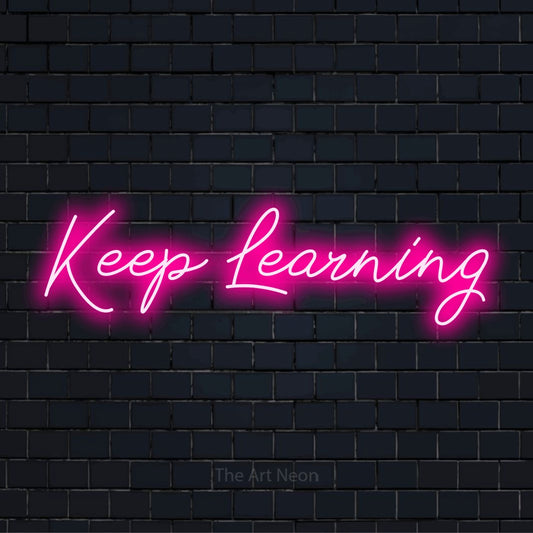 "Keep Learning" glowing LED neon sign on a black brick wall