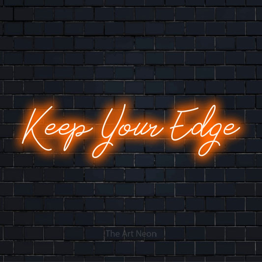"Keep Your Edge" script-style LED neon sign on a black brick wall