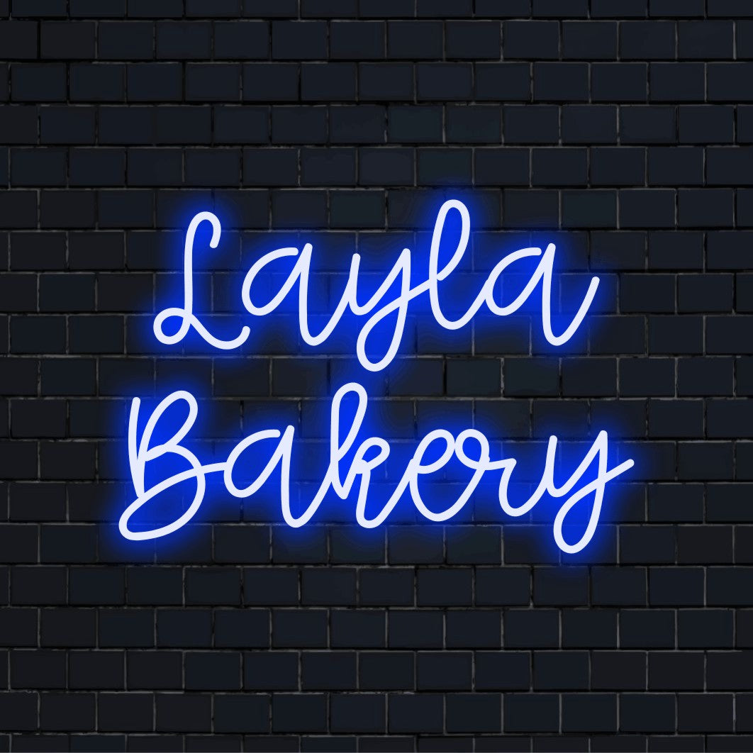 Layla Bakery Personalized Neon Light with bright neon lettering against black brick wall