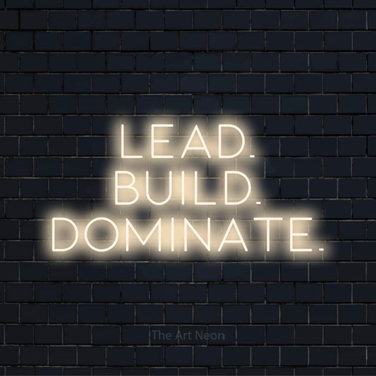 "Lead. Build. Dominate." script-style LED neon sign on a black brick wall