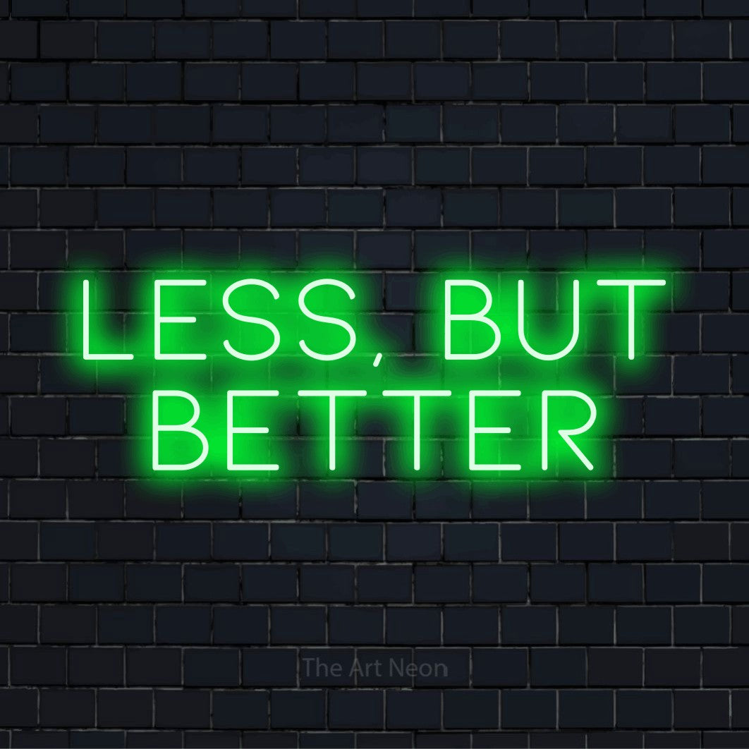 "Less, But Better" neon text design on a black brick wall