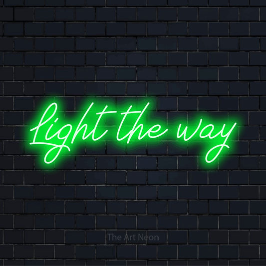 "Light The Way" glowing LED neon sign on a black brick wall