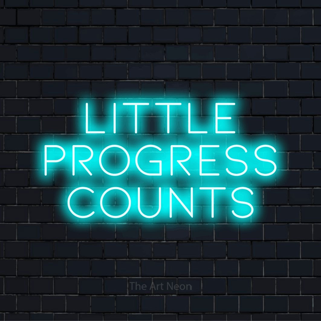 "Little Progress Counts" glowing LED neon sign on a black brick wall