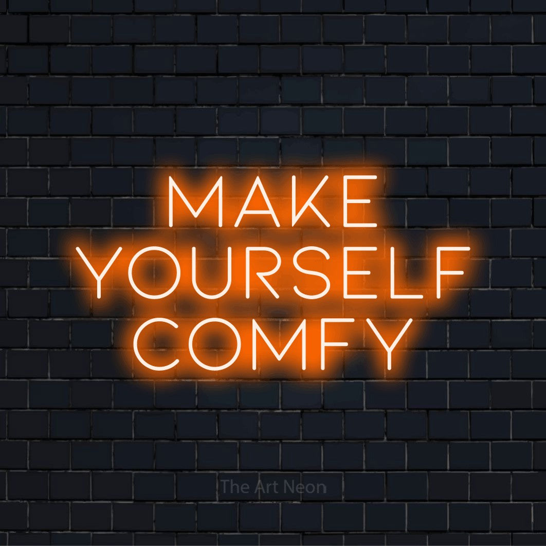 "Make Yourself Comfy" LED neon sign on a black brick wall