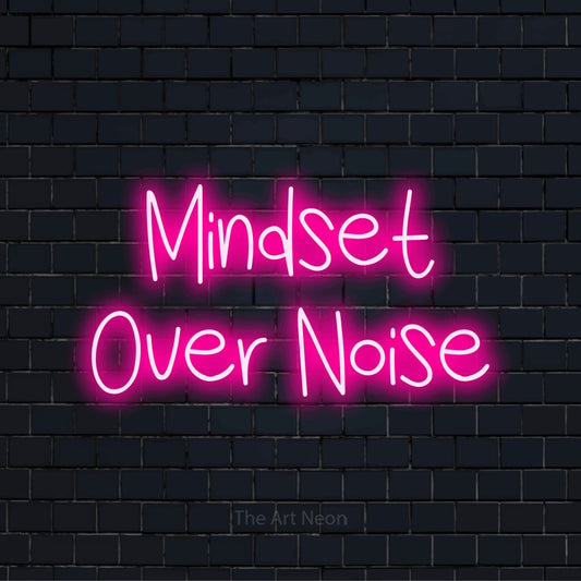 "Mindset Over Noise" script-style LED neon sign on a black brick wall