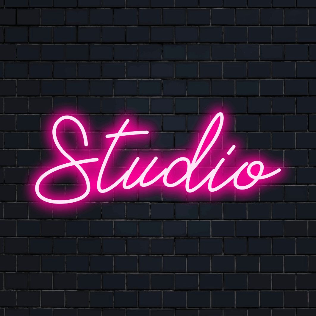 LED-Neonschild mit dem Text „Studio“ auf dunkler Ziegelwand