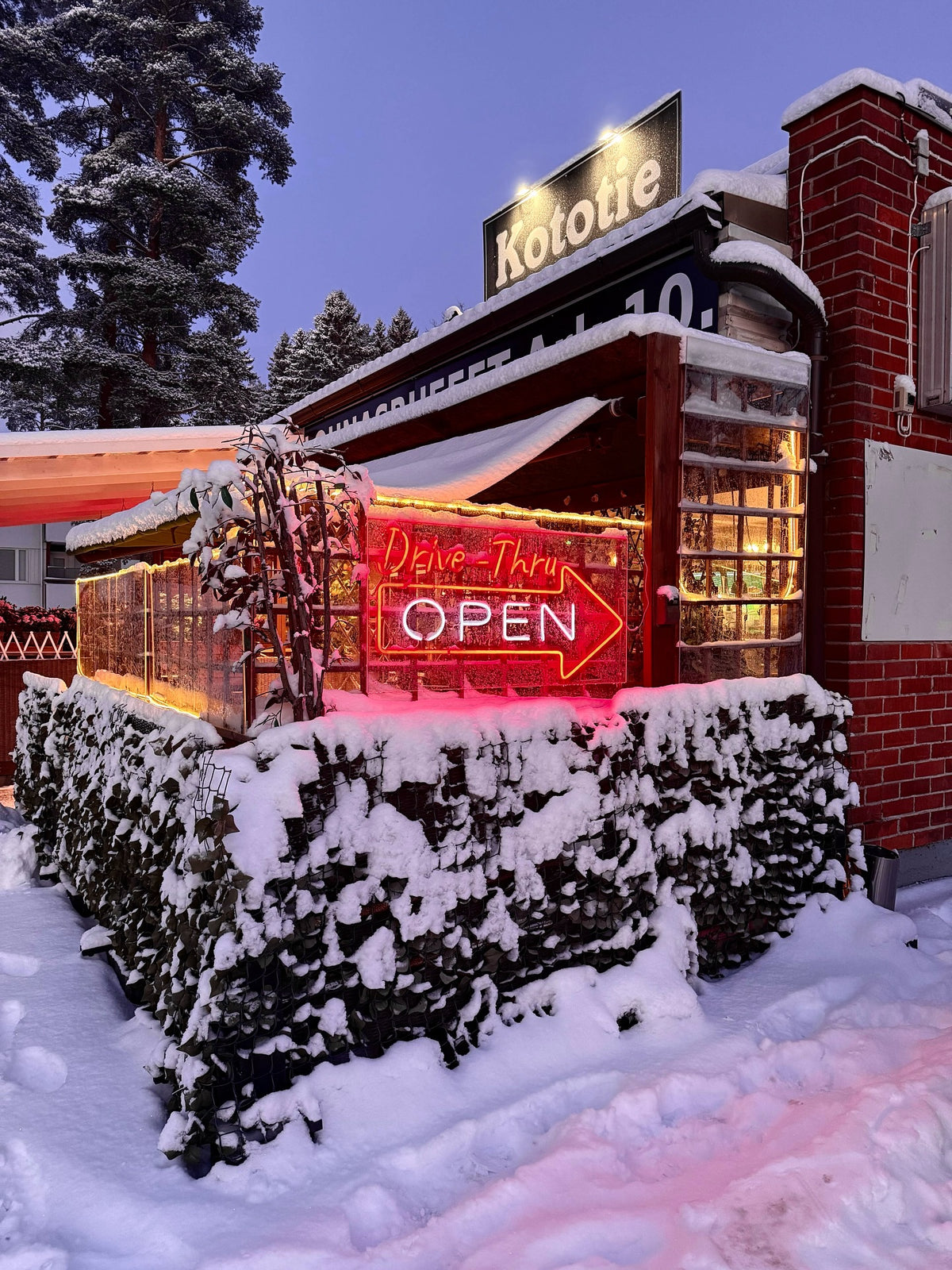 Red OPEN LED neon sign outside a restaurant in snowy weather