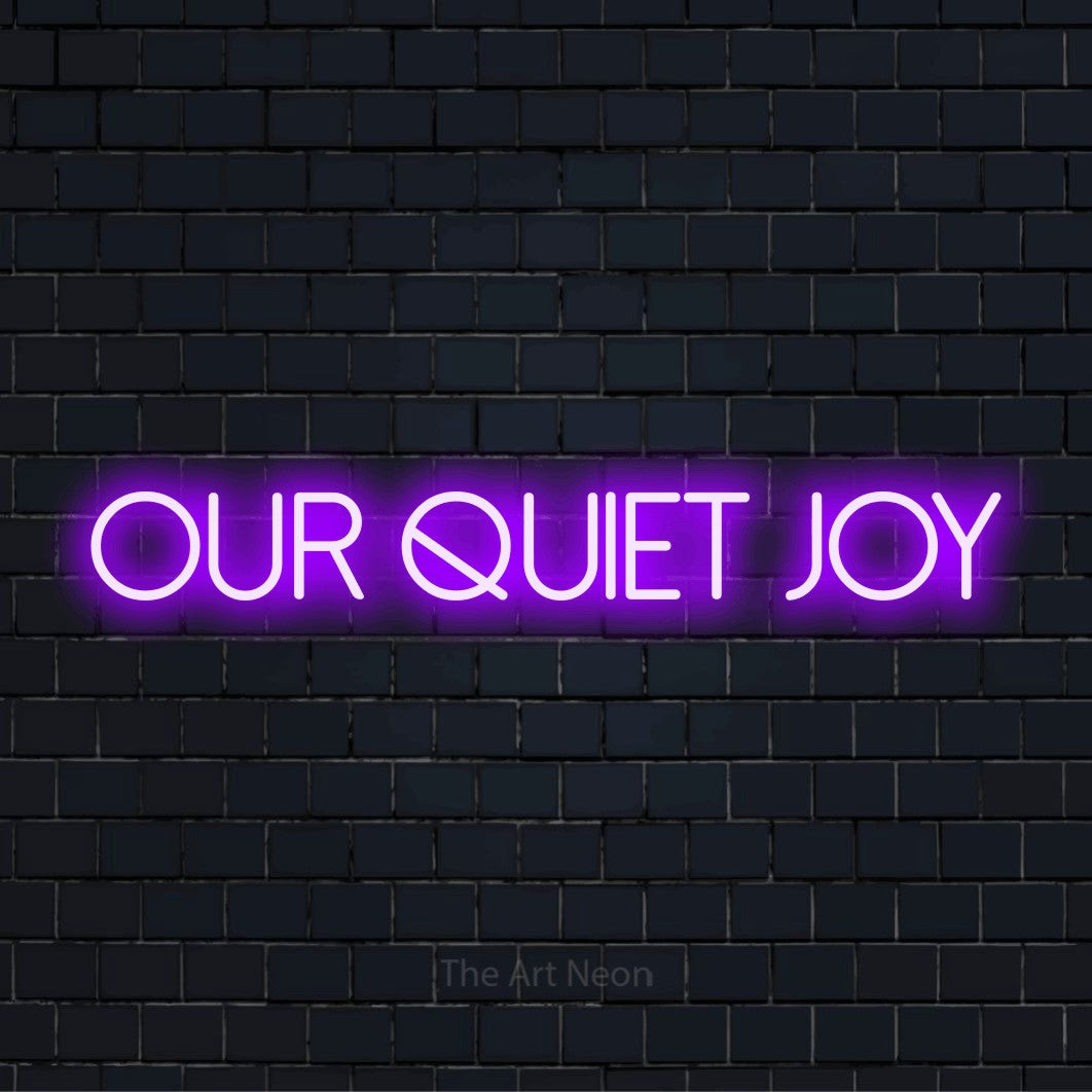 "Our Quiet Joy" glowing LED neon sign on a black brick wall