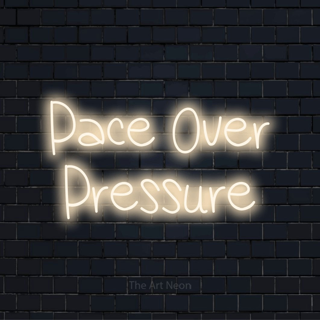 "Pace Over Pressure" script-style LED neon sign on a black brick wall