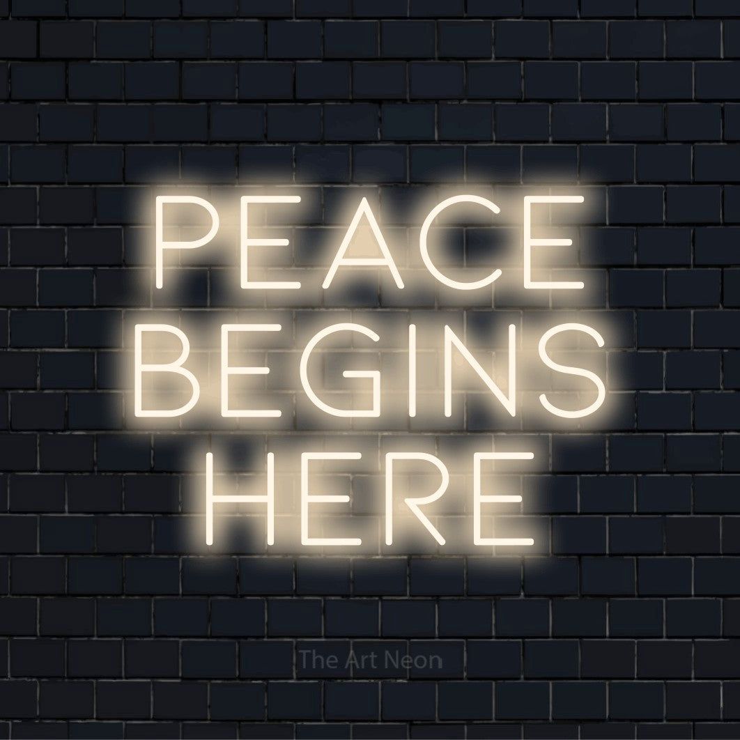 "Peace Begins Here" glowing LED neon sign on a black brick wall