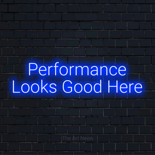 "Performance Looks Good Here" neon text design on a black brick wall