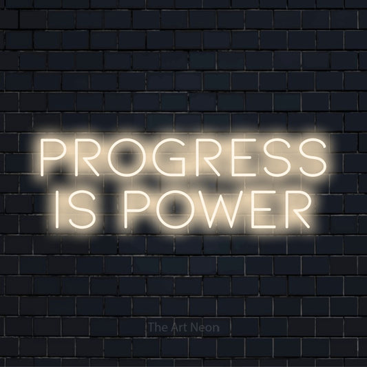 "Progress Is Power" LED neon sign on a black brick wall