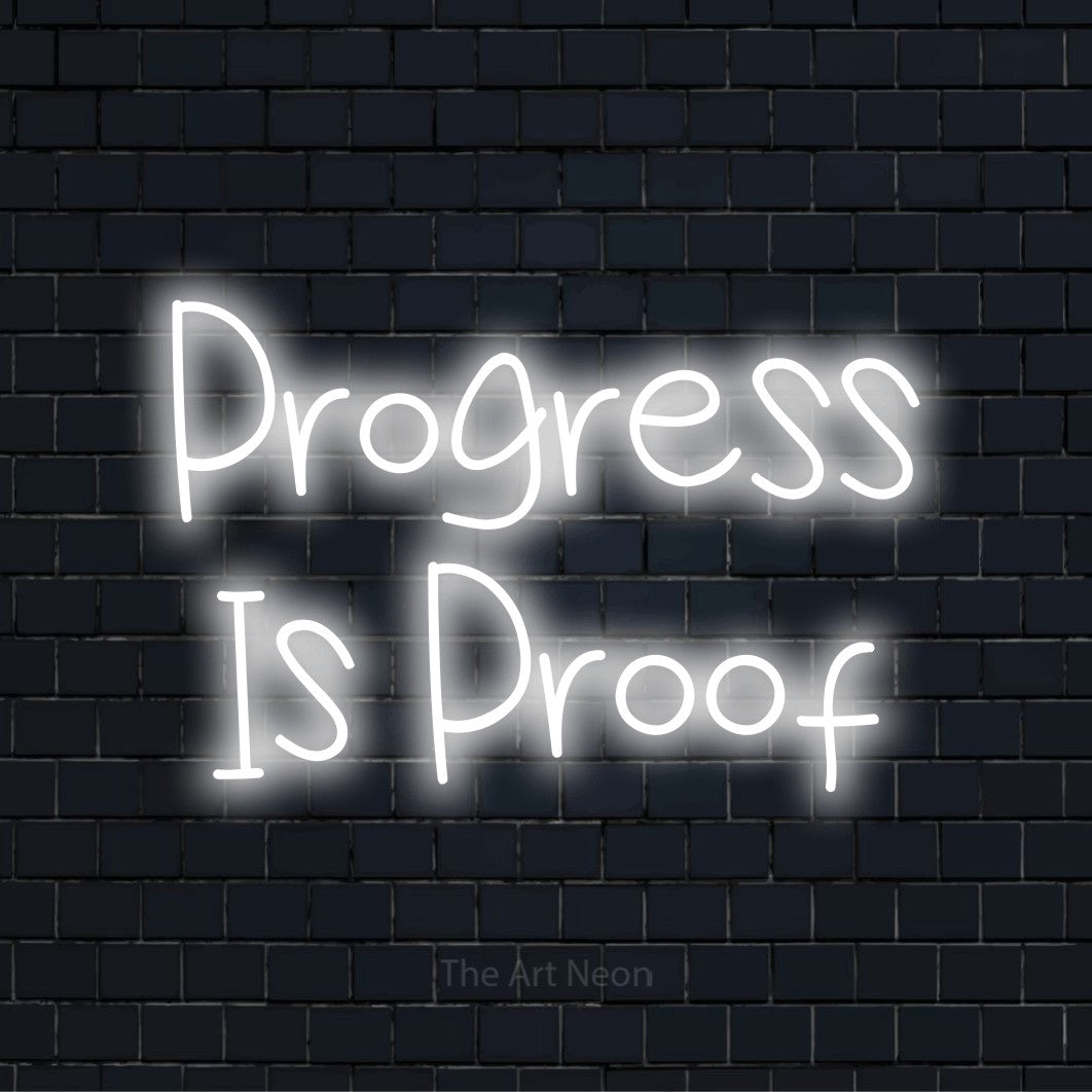 "Progress Is Proof" glowing LED neon sign on a black brick wall