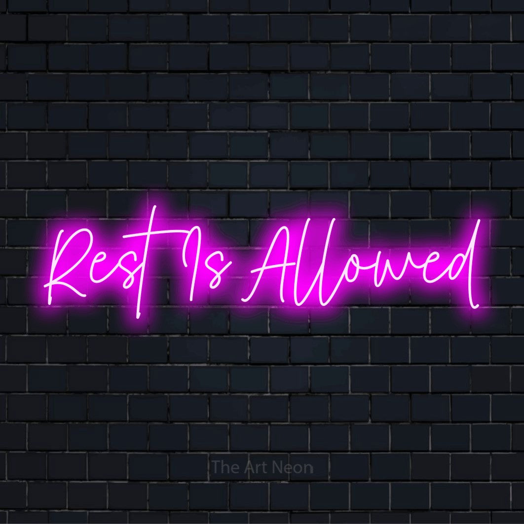 "Rest Is Allowed" script-style LED neon sign on a black brick wall