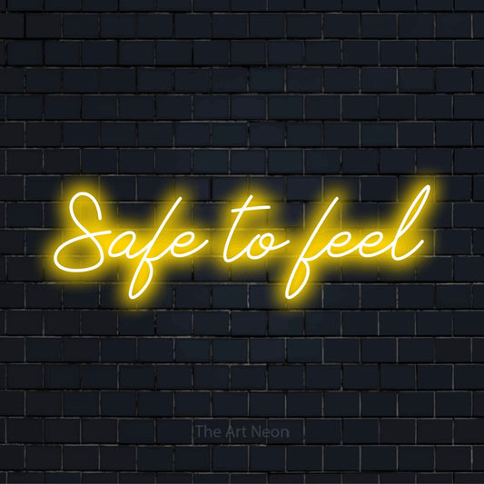 "Safe To Feel" glowing LED neon sign on a black brick wall