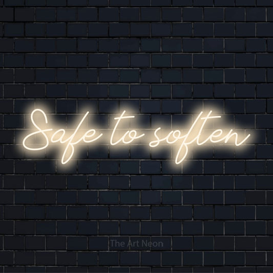 "Safe To Soften" glowing LED neon sign on a black brick wall
