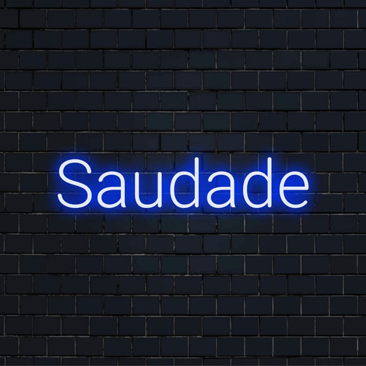 Saudade LED Neon Sign, glowing lettering on dark brick wall