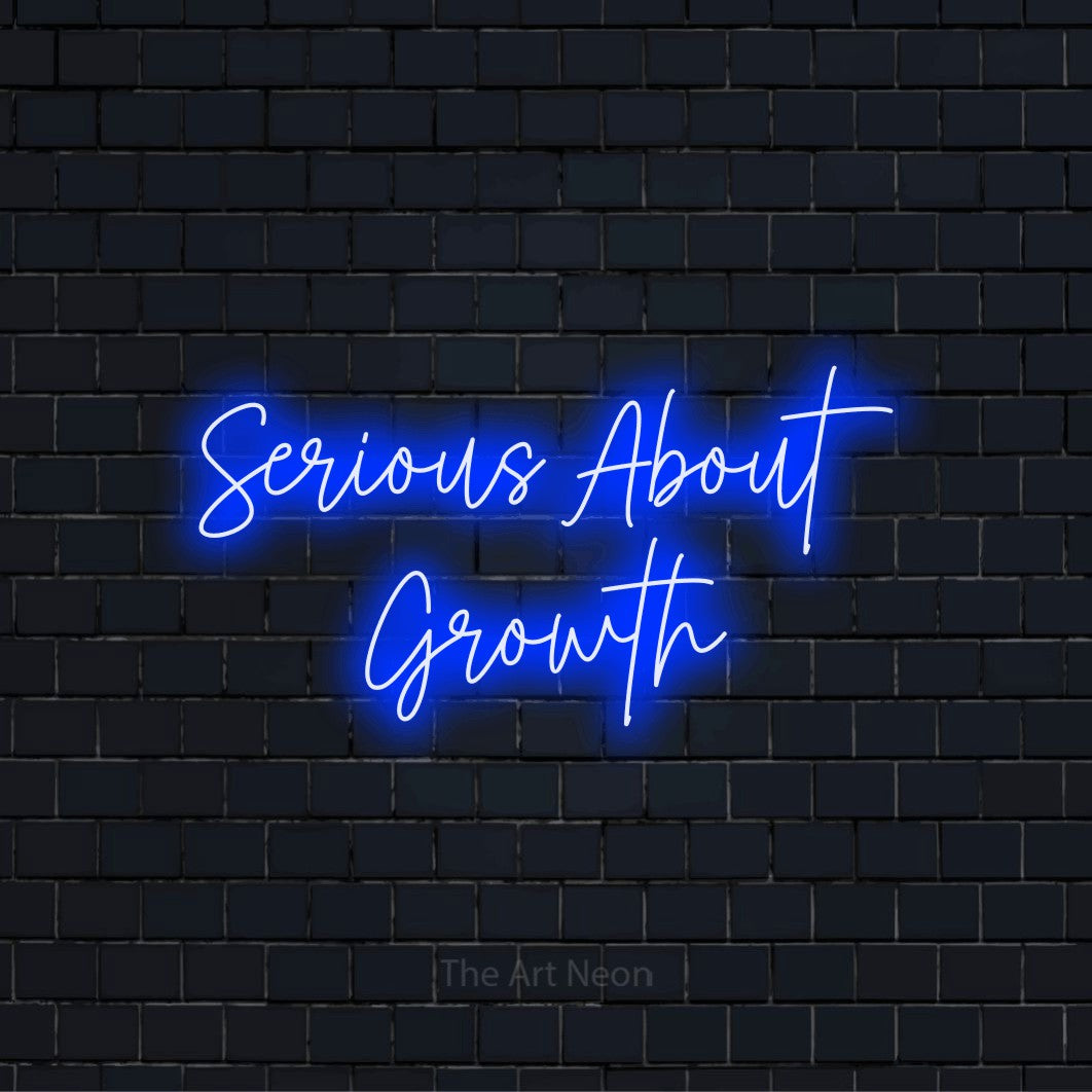"Serious About Growth" script-style LED neon sign on a black brick wall
