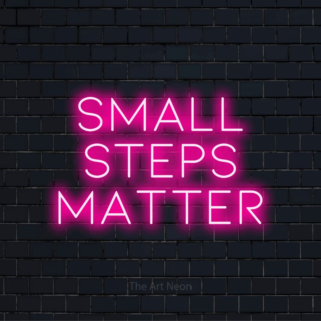 "Small Steps Matter" LED neon sign on a black brick wall
