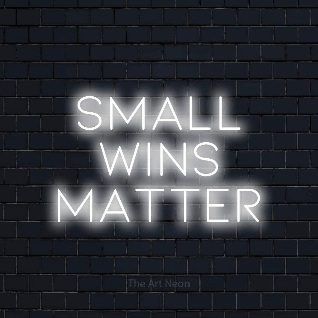 "Small Wins Matter" text design with neon effect on a black brick wall