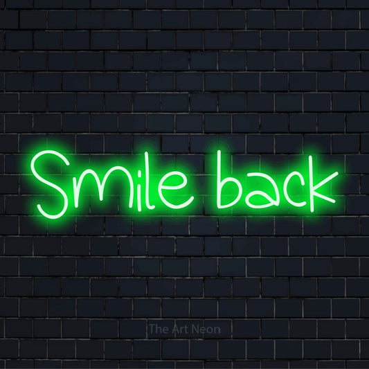 "Smile Back" text design with neon effect on a black brick wall