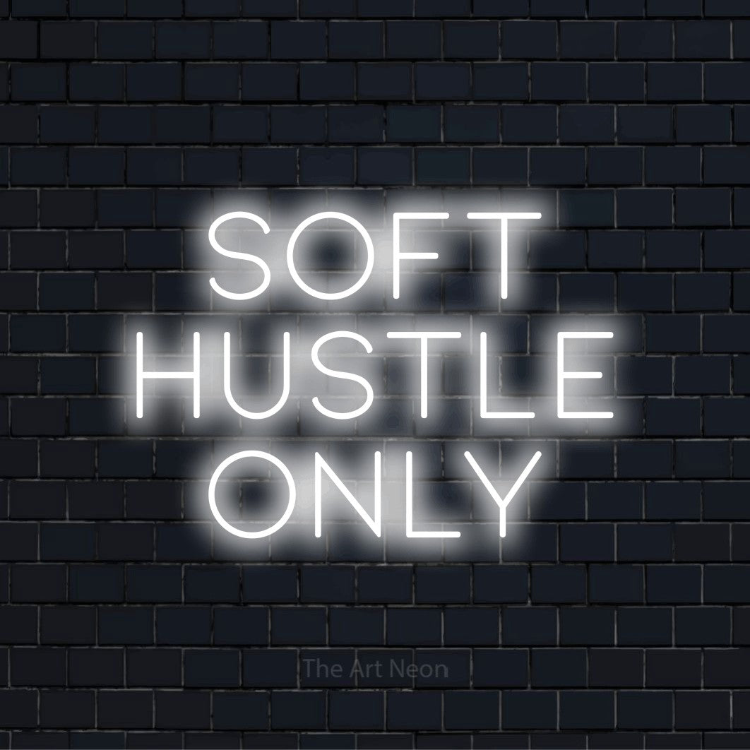 "Soft Hustle Only" script-style LED neon sign on a black brick wall