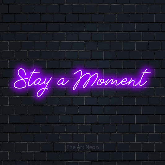 "Stay A Moment" neon text design on a black brick wall