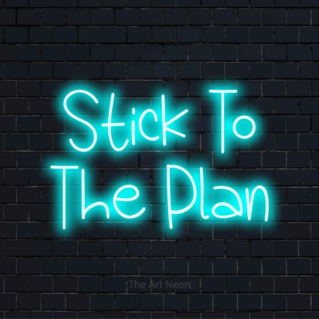 "Stick To The Plan" script-style LED neon sign on a black brick wall