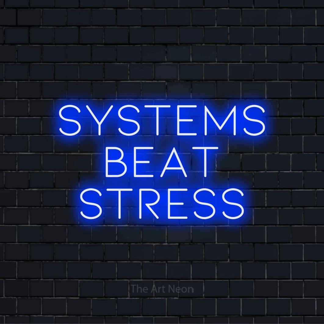 "Systems Beat Stress" LED neon sign on a black brick wall