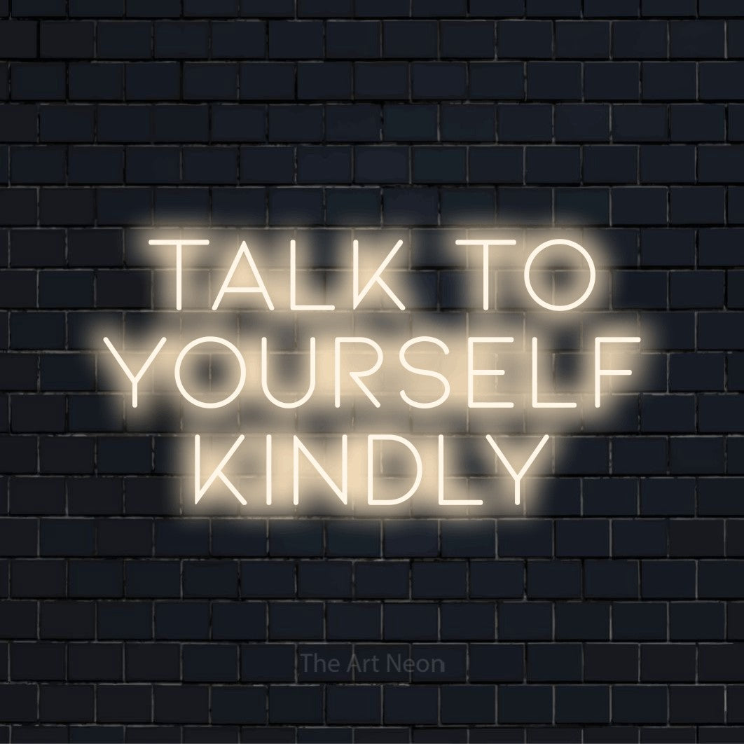 "Talk To Yourself Kindly" neon text design on a black brick wall